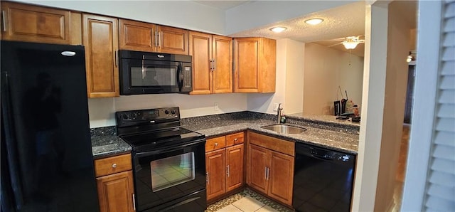 kitchen with brown cabinets, a sink, a textured ceiling, and black appliances