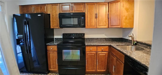 kitchen with black appliances, dark stone countertops, brown cabinetry, and a sink