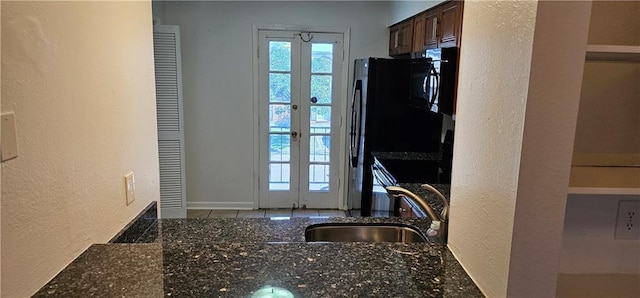 kitchen with dark stone countertops, black microwave, a sink, and french doors