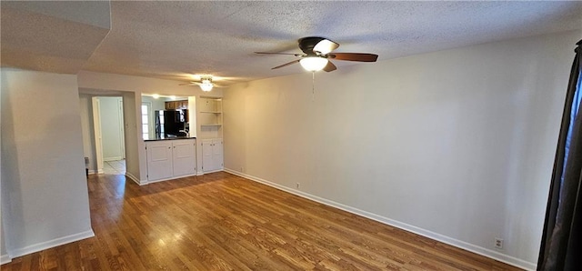 spare room featuring a ceiling fan, a textured ceiling, baseboards, and wood finished floors