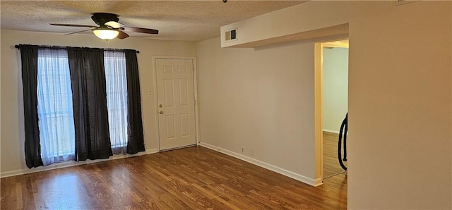 spare room featuring baseboards, a textured ceiling, visible vents, and wood finished floors