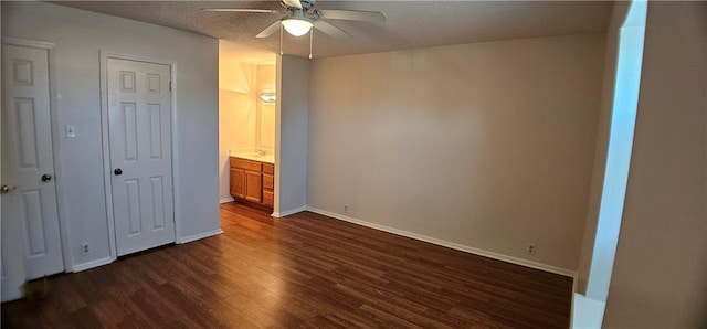 unfurnished bedroom with dark wood-style floors, a textured ceiling, baseboards, and a ceiling fan