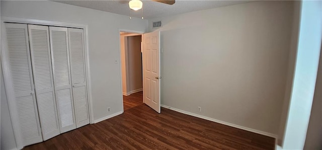 unfurnished bedroom with baseboards, visible vents, dark wood-style flooring, a textured ceiling, and a closet