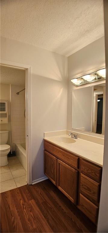 full bathroom featuring a textured ceiling, vanity, wood finished floors, and toilet