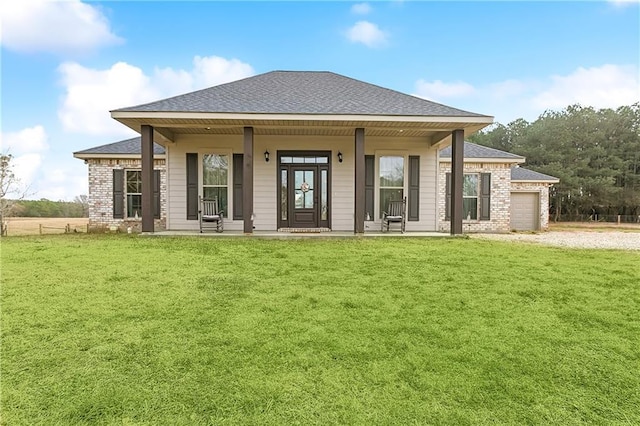 rear view of house featuring a porch, a garage, and a yard