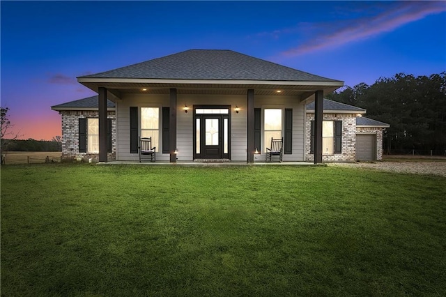 view of front facade featuring a porch, a garage, and a lawn