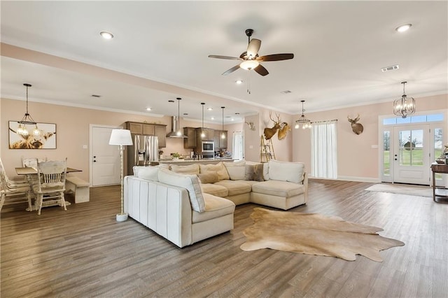 living room featuring ornamental molding, ceiling fan with notable chandelier, and hardwood / wood-style floors