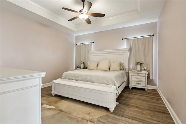 bedroom with ornamental molding, wood-type flooring, ceiling fan, and a tray ceiling