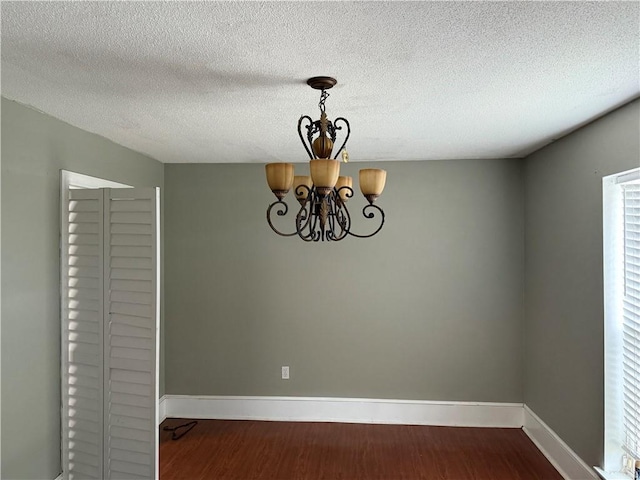 unfurnished room featuring wood-type flooring, a chandelier, and a textured ceiling