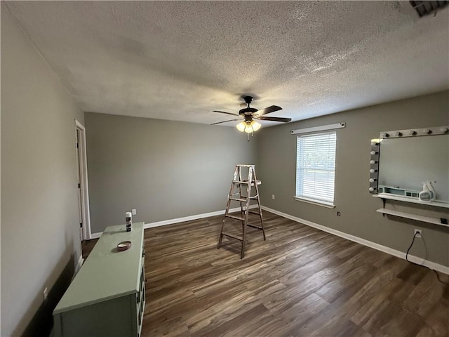 living area featuring ceiling fan, dark hardwood / wood-style flooring, and a textured ceiling