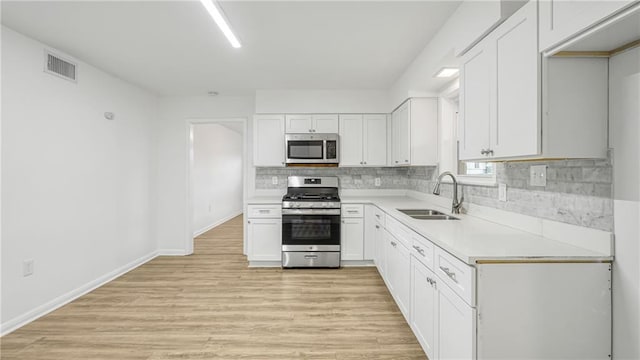 kitchen featuring tasteful backsplash, appliances with stainless steel finishes, sink, and white cabinets