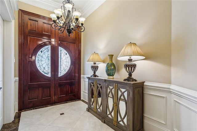 foyer with an inviting chandelier, light tile patterned floors, and ornamental molding