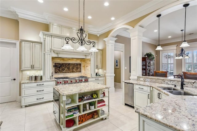 kitchen featuring light stone counters, sink, decorative light fixtures, and decorative columns