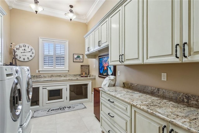 clothes washing area featuring light tile patterned floors, ornamental molding, cabinets, and washing machine and clothes dryer