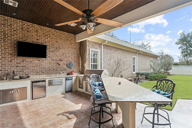 view of patio / terrace featuring an outdoor wet bar, grilling area, ceiling fan, and exterior kitchen