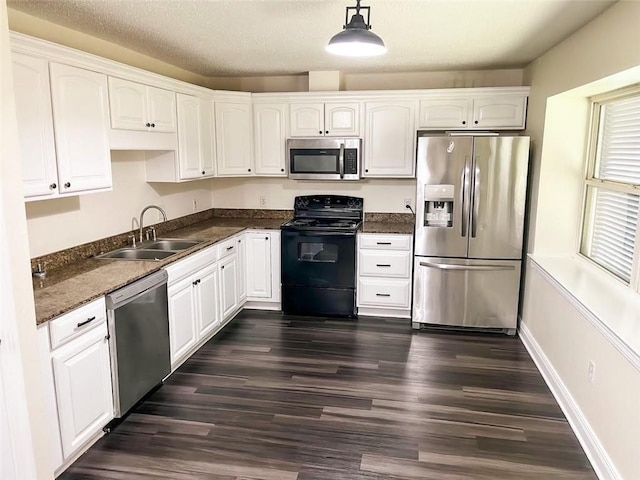 kitchen with sink, appliances with stainless steel finishes, dark hardwood / wood-style floors, white cabinets, and decorative light fixtures