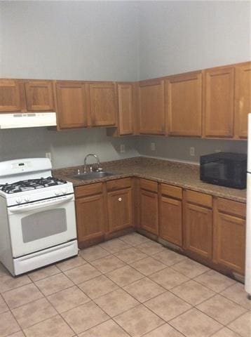 kitchen featuring light tile patterned flooring, a towering ceiling, sink, and white range with gas stovetop