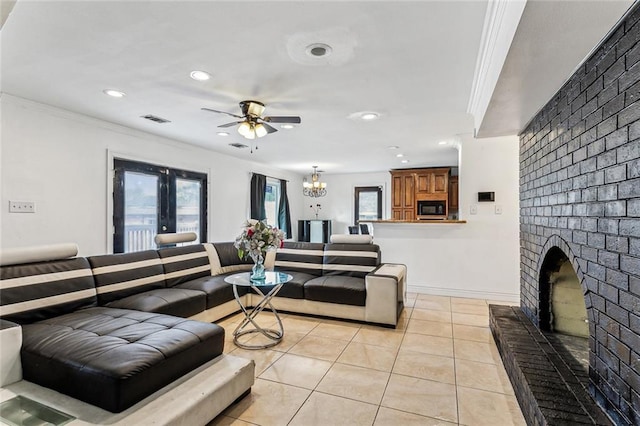 tiled living room featuring crown molding, plenty of natural light, ceiling fan with notable chandelier, and a fireplace