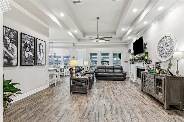 living room with crown molding, hardwood / wood-style floors, a tray ceiling, and ceiling fan