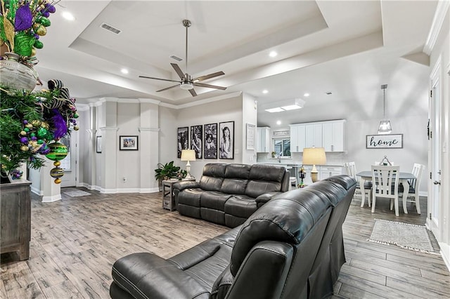 living room with hardwood / wood-style flooring, a raised ceiling, and ceiling fan