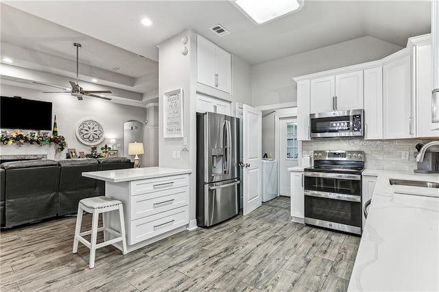 kitchen featuring sink, white cabinets, backsplash, stainless steel appliances, and light wood-type flooring