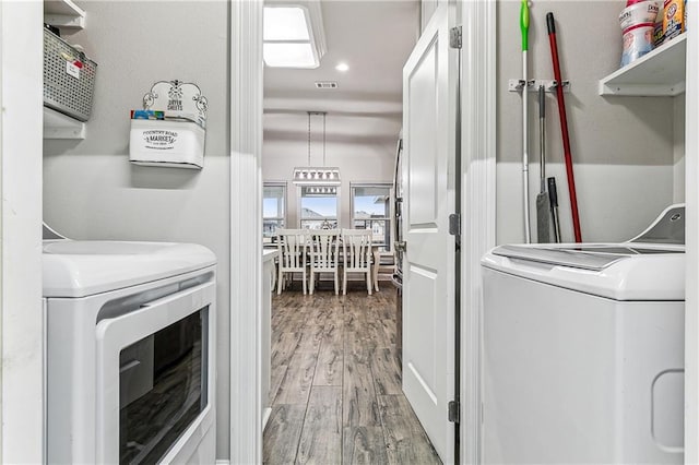 clothes washing area with wood-type flooring and washing machine and dryer