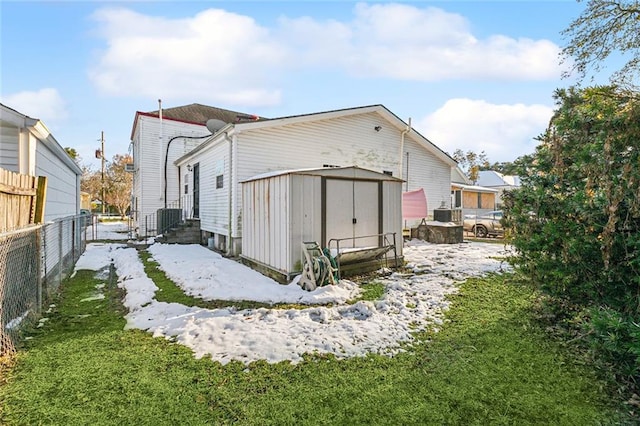 snow covered property featuring a storage shed and a yard