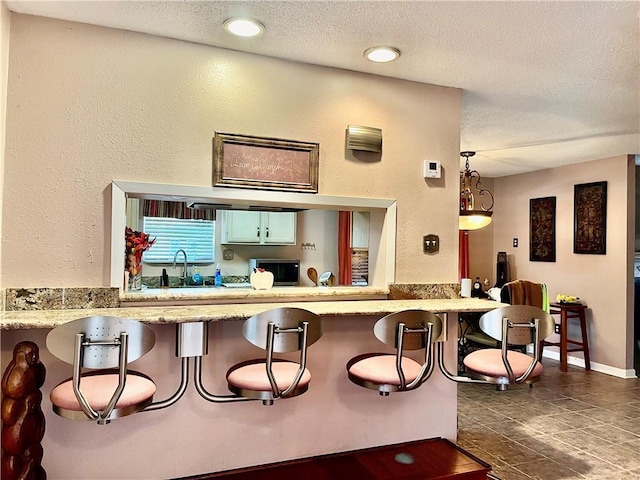 interior space with sink, decorative light fixtures, and a textured ceiling