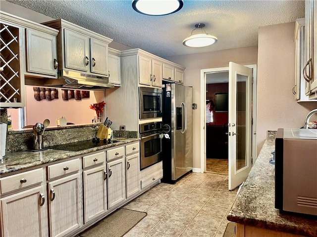 kitchen featuring stainless steel appliances, light tile patterned flooring, stone countertops, and a textured ceiling