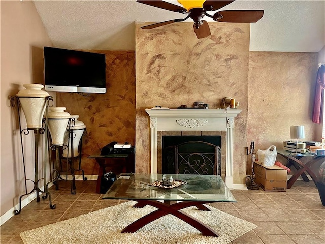 living area featuring lofted ceiling, a textured ceiling, a tile fireplace, ceiling fan, and tile patterned flooring