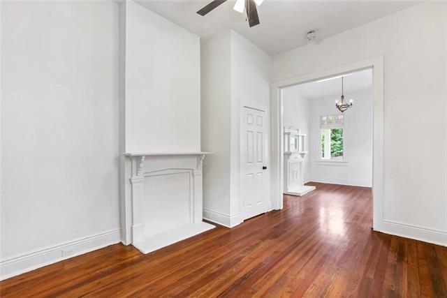 unfurnished living room featuring dark hardwood / wood-style flooring and ceiling fan with notable chandelier