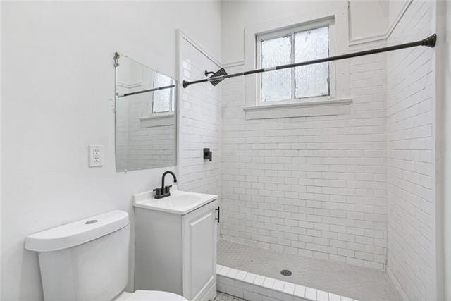 bathroom with vanity, toilet, and a tile shower