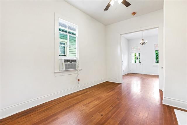 spare room with cooling unit, hardwood / wood-style floors, and ceiling fan with notable chandelier