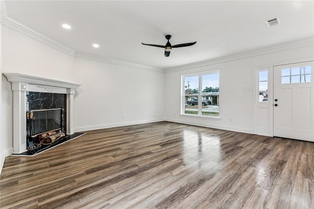 unfurnished living room featuring ceiling fan, ornamental molding, a premium fireplace, and wood-type flooring