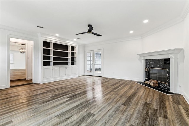 unfurnished living room featuring a fireplace, hardwood / wood-style flooring, ornamental molding, ceiling fan, and french doors