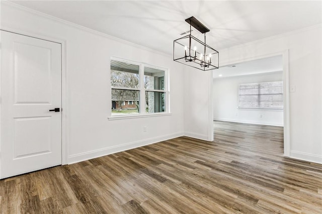 unfurnished dining area with a notable chandelier, hardwood / wood-style flooring, and ornamental molding