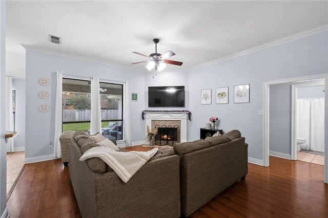 living room with dark wood-type flooring, ornamental molding, and ceiling fan