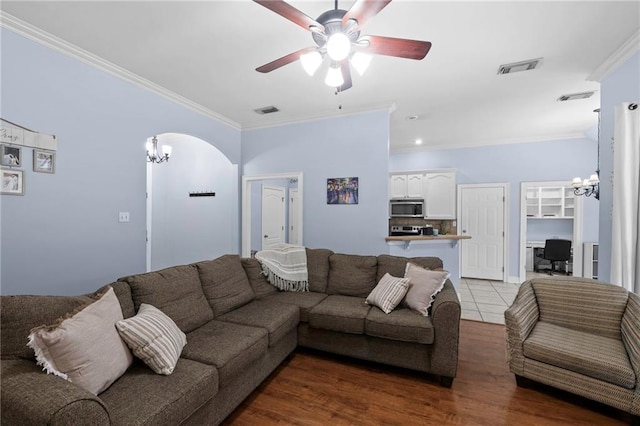 living room with crown molding, ceiling fan with notable chandelier, and hardwood / wood-style flooring