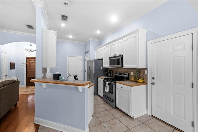 kitchen featuring white cabinetry, butcher block countertops, backsplash, and stainless steel appliances