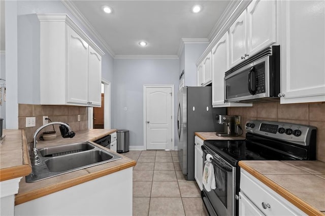 kitchen with stainless steel appliances, sink, tile counters, and white cabinets