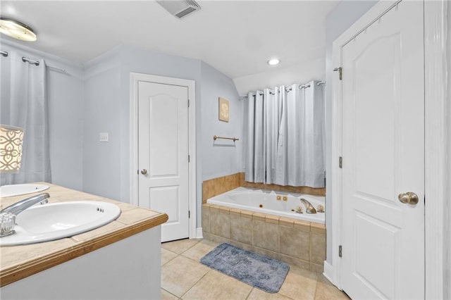 bathroom with tile patterned flooring, vanity, and tiled tub