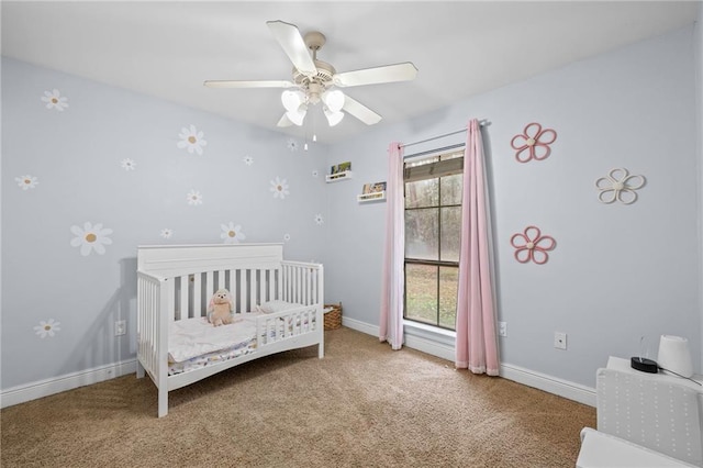 bedroom featuring a nursery area, carpet flooring, and ceiling fan