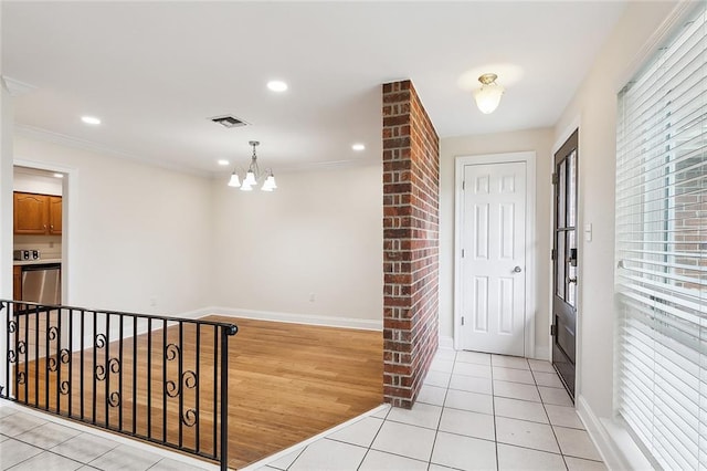 tiled foyer entrance featuring ornamental molding and an inviting chandelier