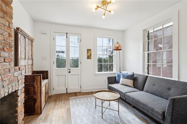 living room featuring a notable chandelier, a fireplace, and light hardwood / wood-style floors