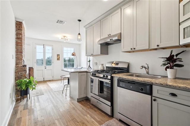 kitchen with appliances with stainless steel finishes, decorative light fixtures, sink, and gray cabinetry