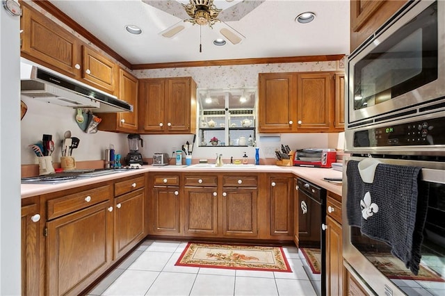 kitchen featuring a sink, brown cabinets, under cabinet range hood, and stainless steel appliances