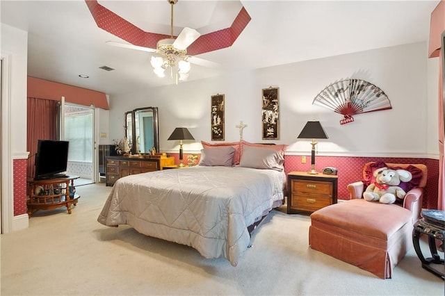 bedroom with light colored carpet, ceiling fan, wainscoting, and visible vents