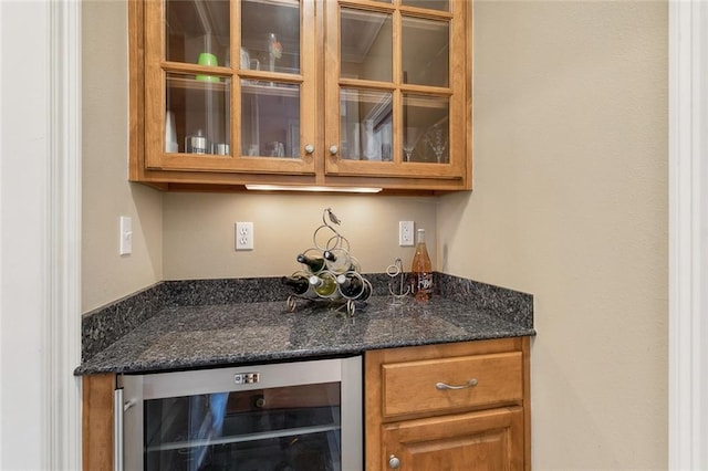 bar featuring beverage cooler and dark stone counters