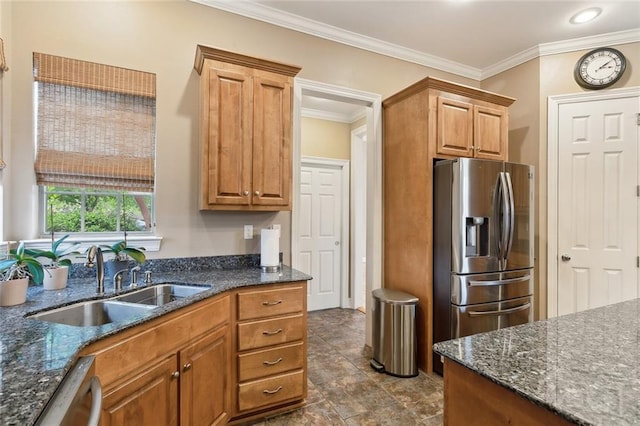 kitchen with ornamental molding, stainless steel appliances, dark stone countertops, a sink, and brown cabinetry