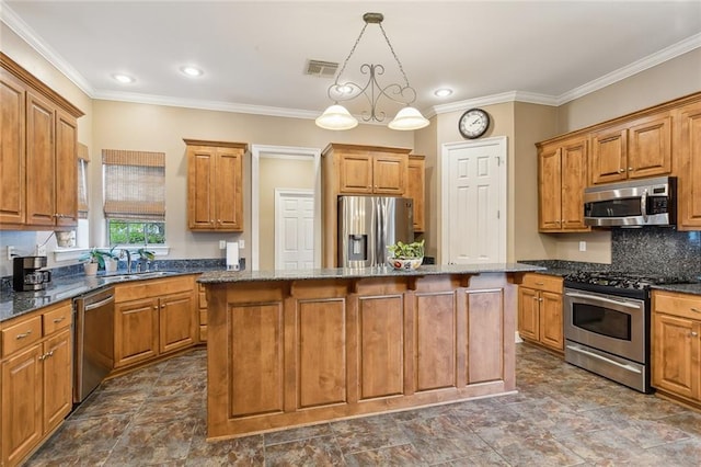 kitchen featuring sink, a center island, hanging light fixtures, appliances with stainless steel finishes, and dark stone counters